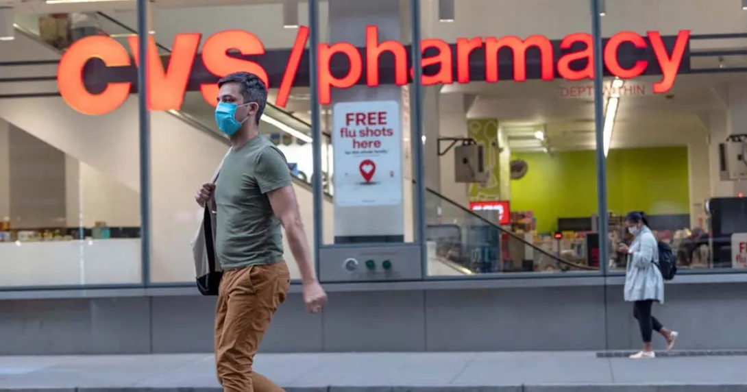 A masked person walking by a CVS pharmacy.
A masked person walking by a CVS pharmacy.
