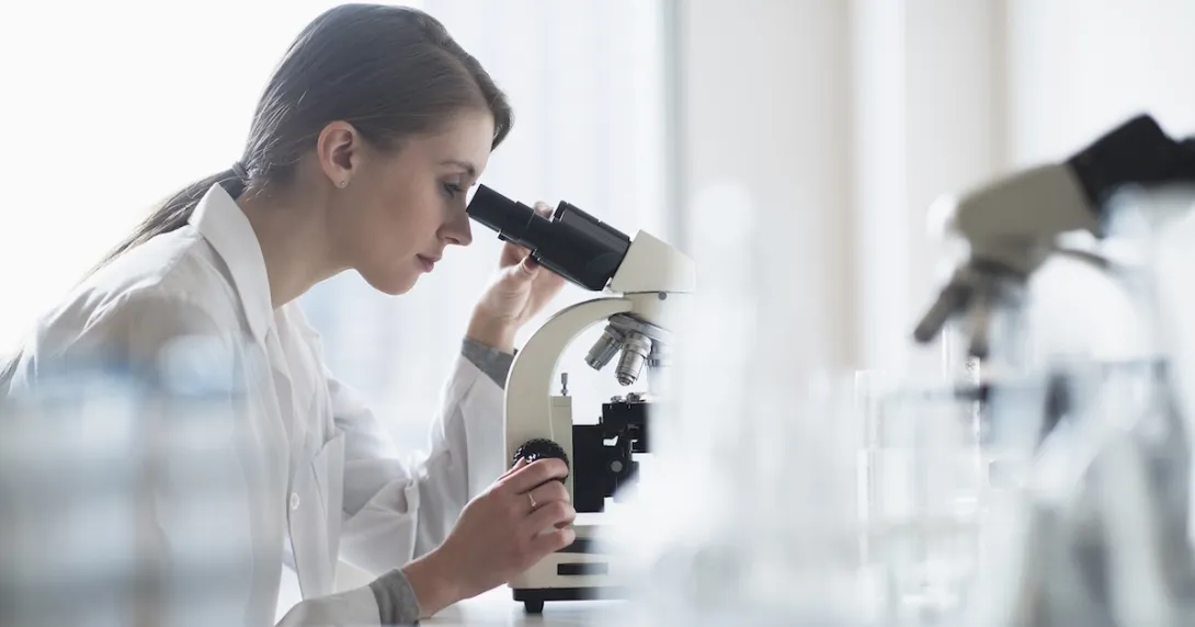 Technician looking into a microscope Technician looking into a microscope