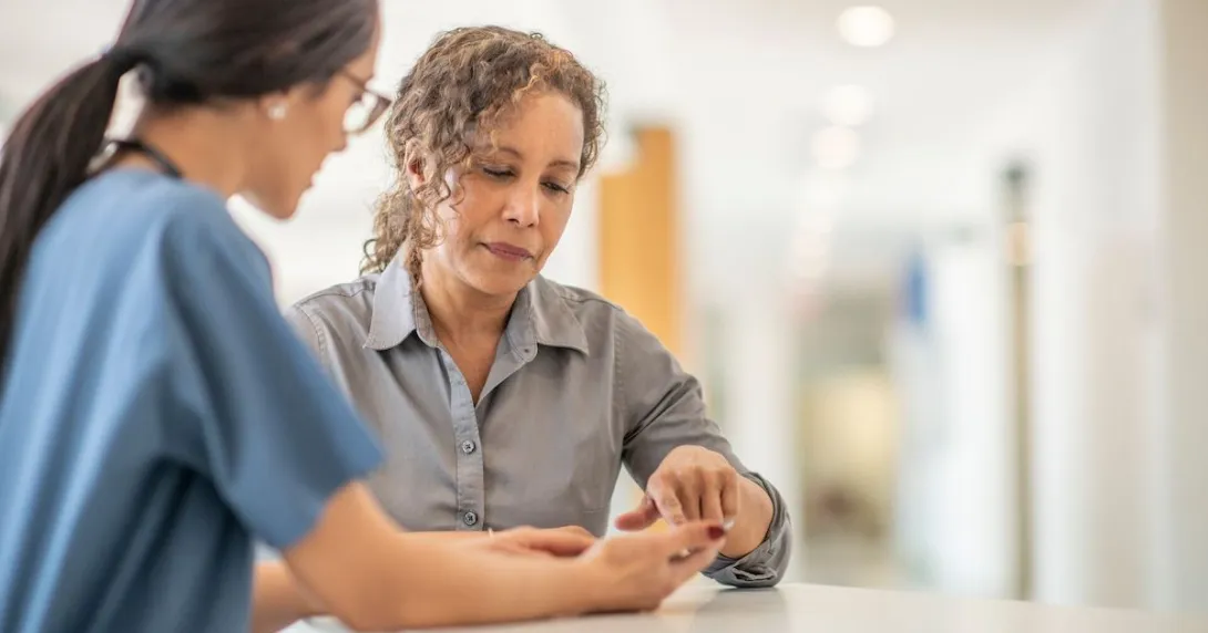 A healthcare provider speaking to an individual in a clinical setting A healthcare provider speaking to an individual in a clinical setting