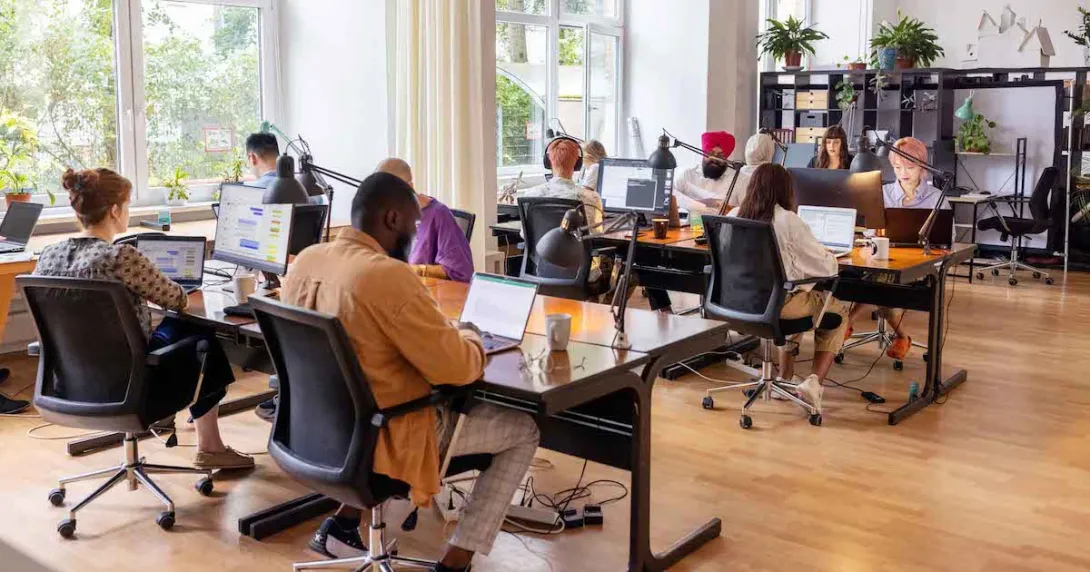 Employees sitting in an open working room Employees sitting in an open working room