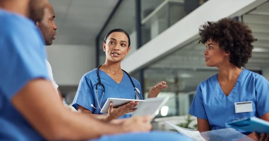 Four people in nursing unifroms, one wearing stethoscope Four people in nursing uniforms, one wearing stethoscope