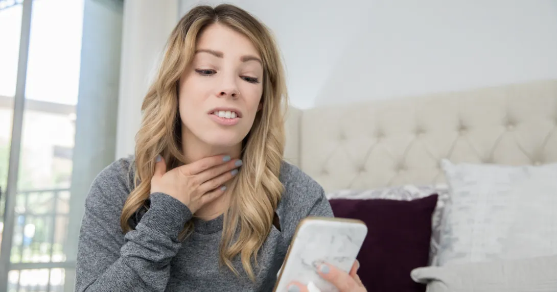 Person on a cellphone holding their throat
Person on a cellphone holding their throat