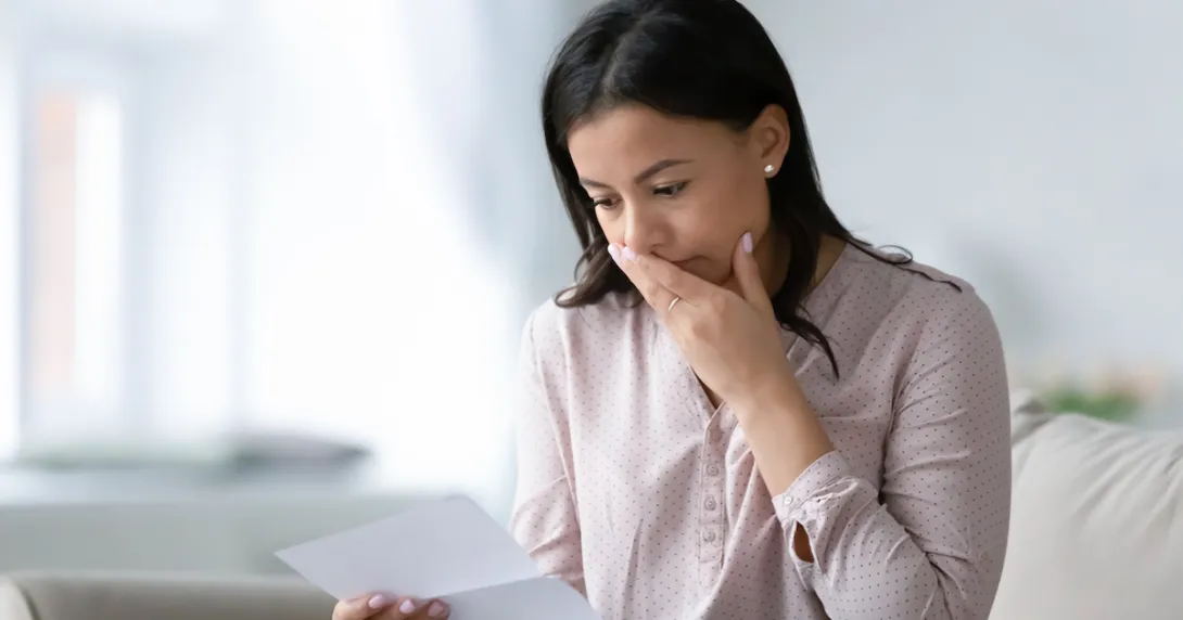 Person with their mouth covered looking at a piece of paper
Person with their mouth covered looking at a piece of paper