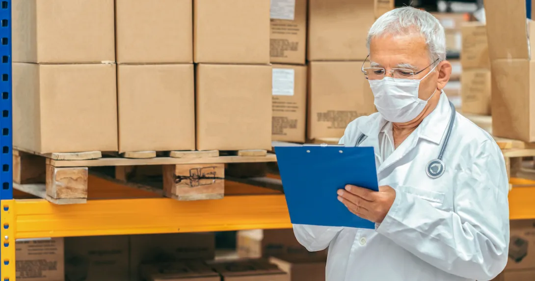 Healthcare provider looking at a document with boxes behind them
Healthcare provider looking at a document with boxes behind them