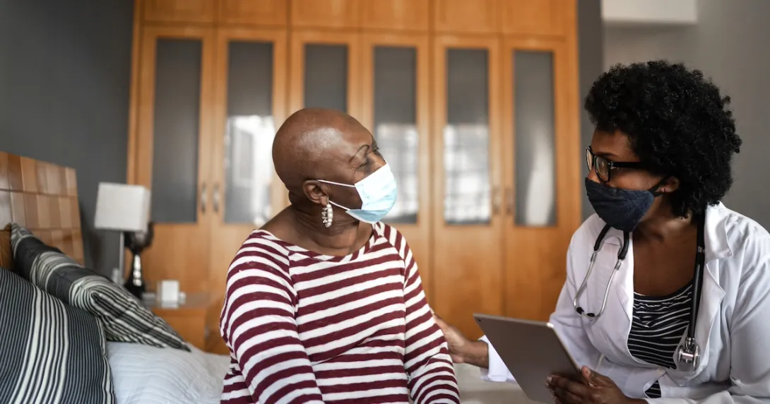 Two individuals sitting in a home looking at each other while wearing face masks Two individuals sitting in a home looking at each other while wearing face masks