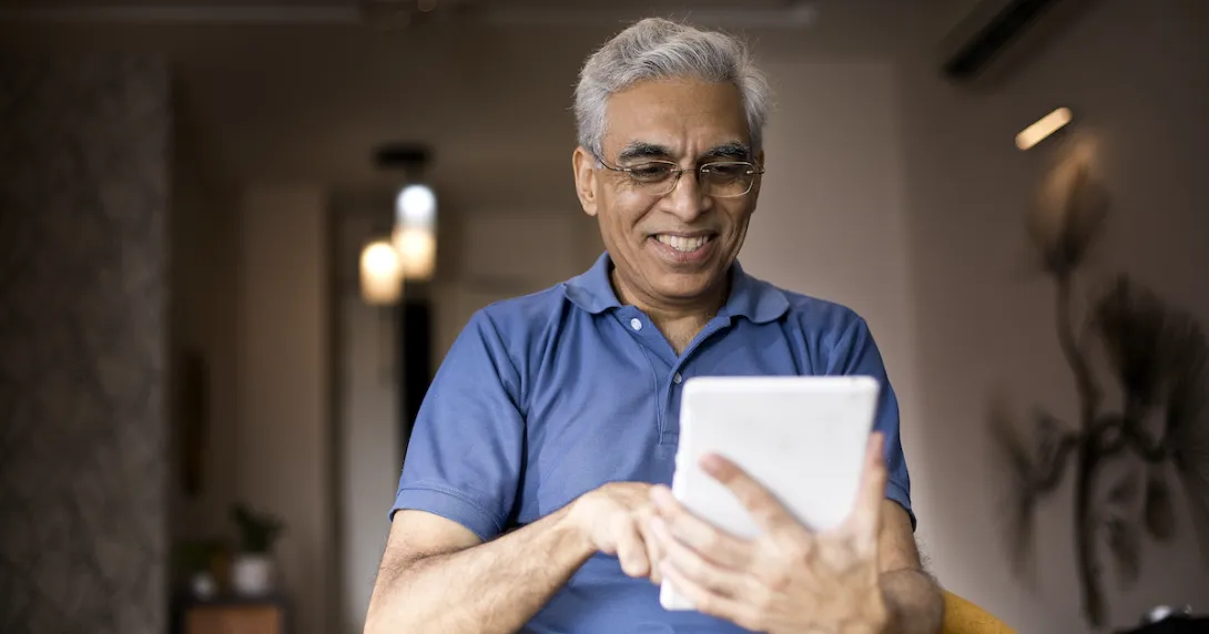 Person wearing a blue shirt and holding a tablet in the living room of a home
Person wearing a blue shirt and holding a tablet in the living room of a home