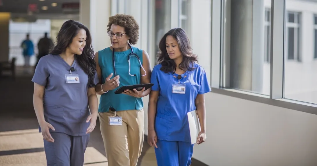 Three healthcare providers walking through a hall while looking at a tablet
Three healthcare providers walking through a hall while looking at a tablet