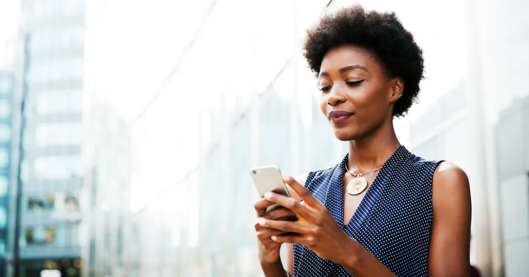 Person standing on a city block looking at their phone Person standing on a city block looking at their phone