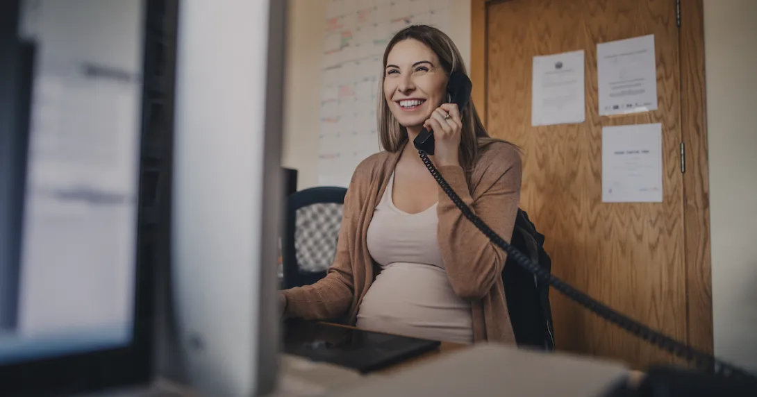 Pregnant person sitting at a desk talking on the phone while looking at a computer
Pregnant person sitting at a desk talking on the phone while looking at a computer