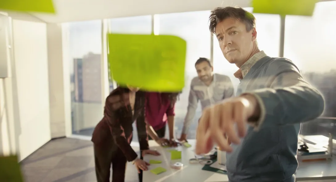 People standing in a room looking at a wall of post-its