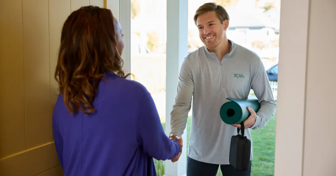 A physical therapist greeting a patient at the door with a yoga mat
A physical therapist greeting a patient at the door with a yoga mat