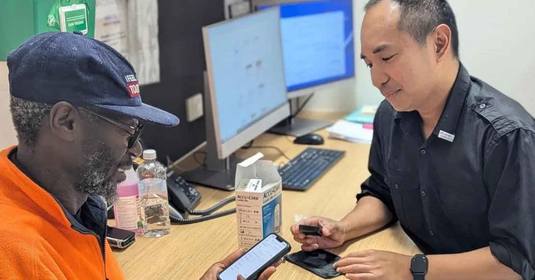 A patient with diabetes being assisted in using a mobile app to track their blood glucose level A patient with diabetes being assisted in using a mobile app to track their blood glucose level