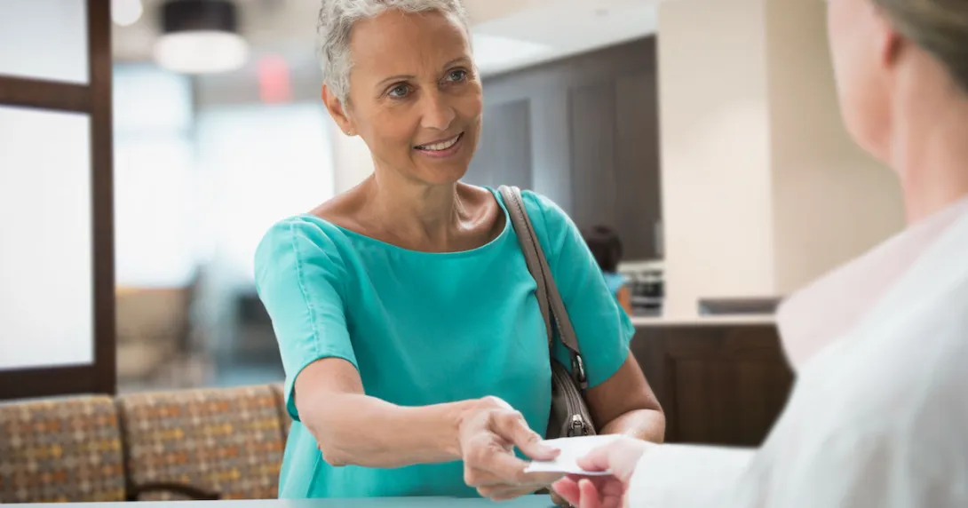 Person handing a piece of paper to a healthcare professional
Person handing a piece of paper to a healthcare professional