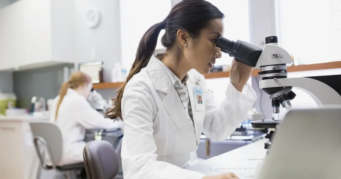 Healthcare professional looking into a microscope Healthcare professional looking into a microscope