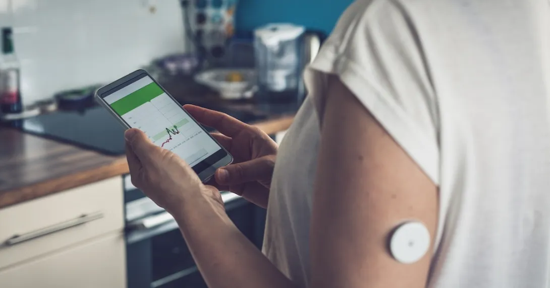 Image of person with glucose patch looking at a smartphone Image of person with glucose patch looking at a smartphone