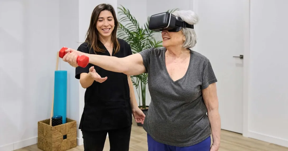 Person doing rehabilitation exercises while wearing a headset and standing next to a PT Person doing rehabilitation exercises while wearing a headset and standing next to a PT