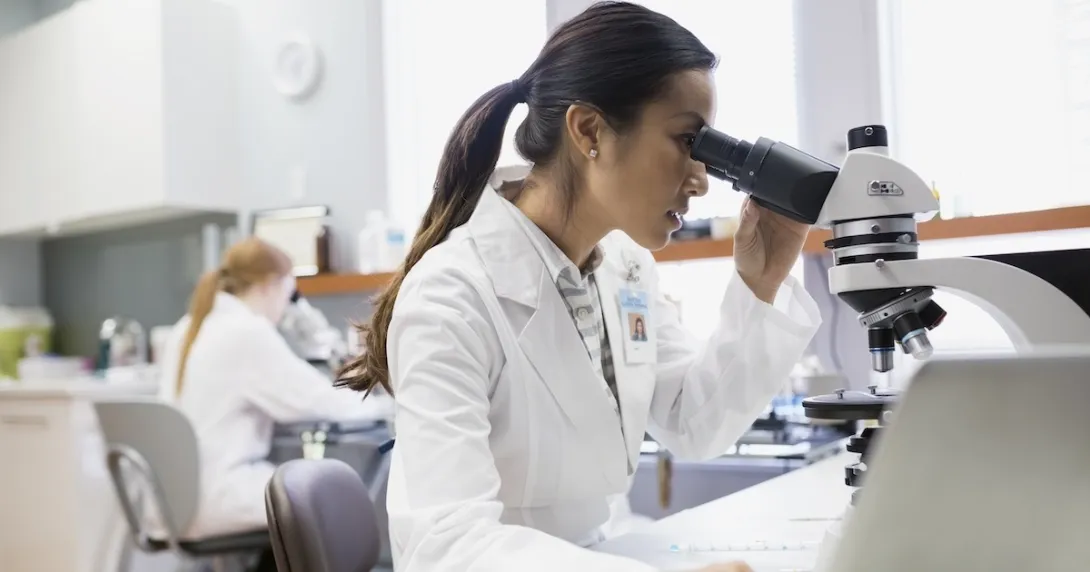 Health care practitioner looking through a microscope Health care practitioner looking through a microscope