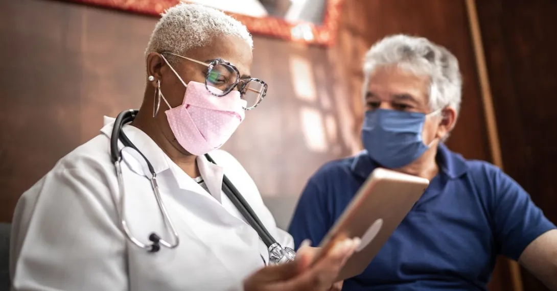 A doctor talking to a patient while holding a tablet.
A doctor talking to a patient while holding a tablet.