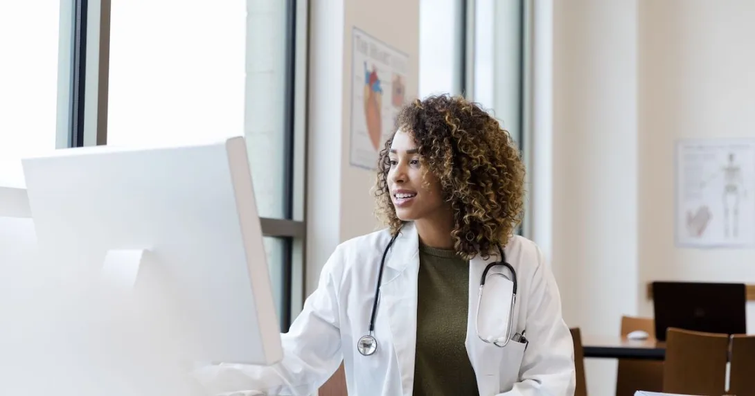 Healthcare provider with a lab coat on sitting at a desk and looking at a computer
Healthcare provider with a lab coat on sitting at a desk and looking at a computer