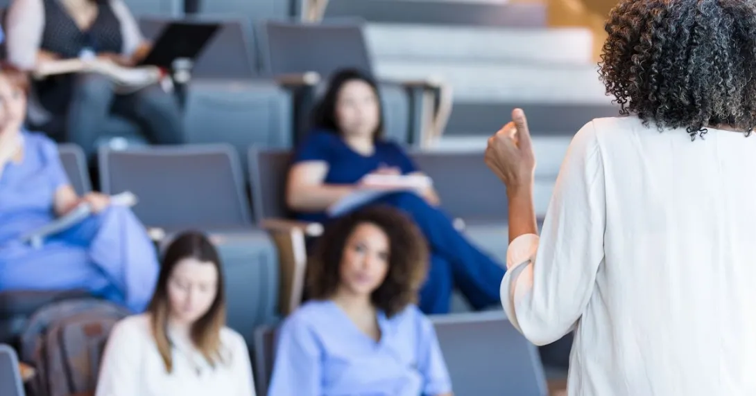 Students in scrubs sitting in a classroom looking at a teacher
Students in scrubs sitting in a classroom looking at a teacher