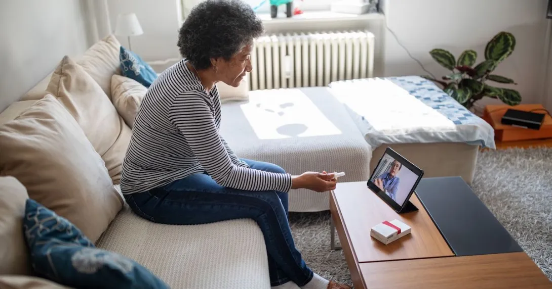 Person sitting on their couch speaking to a healthcare provider on a tablet
Person sitting on their couch speaking to a healthcare provider on a tablet