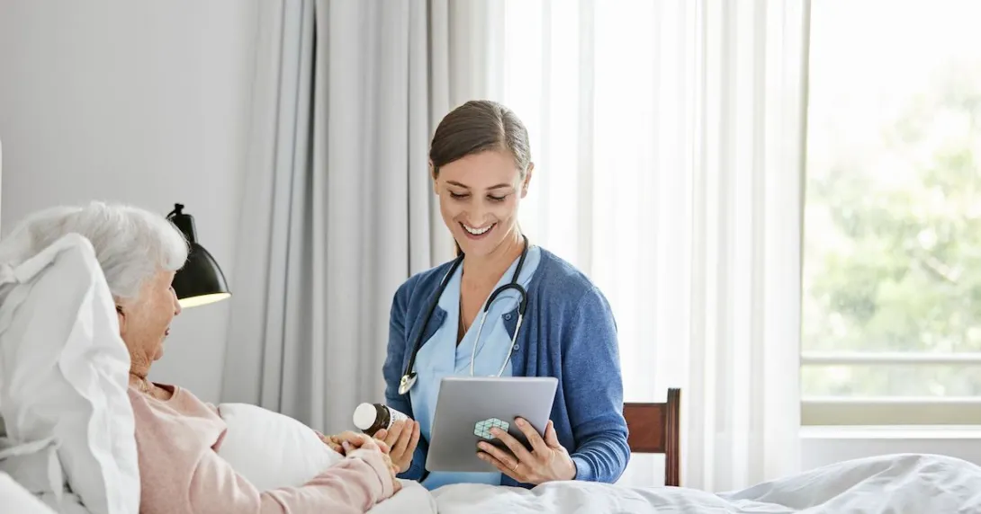 Person lying in bed with a healthcare provider sitting beside them in a chair holding a tablet
Person lying in bed with a healthcare provider sitting beside them in a chair holding a tablet