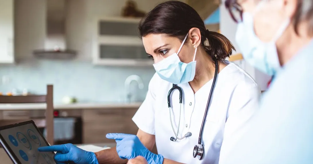 Healthcare providers in lab coats wearing a mask and stethoscope and looking at a screen
Healthcare providers in lab coats wearing a mask and stethoscope and looking at a screen