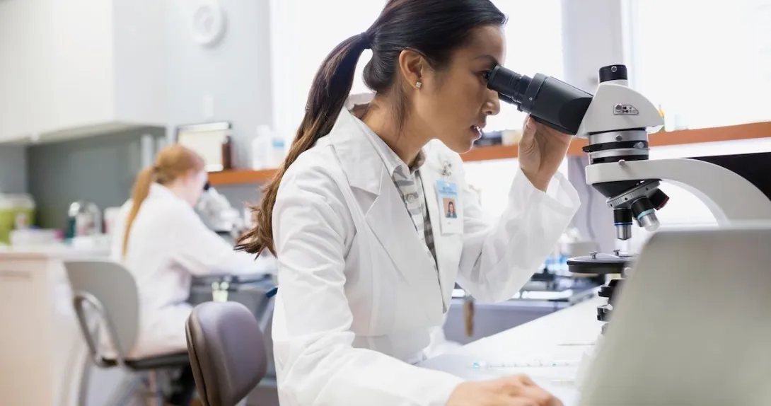 Scientist in a lab looking into a microscope Scientist in a lab looking into a microscope