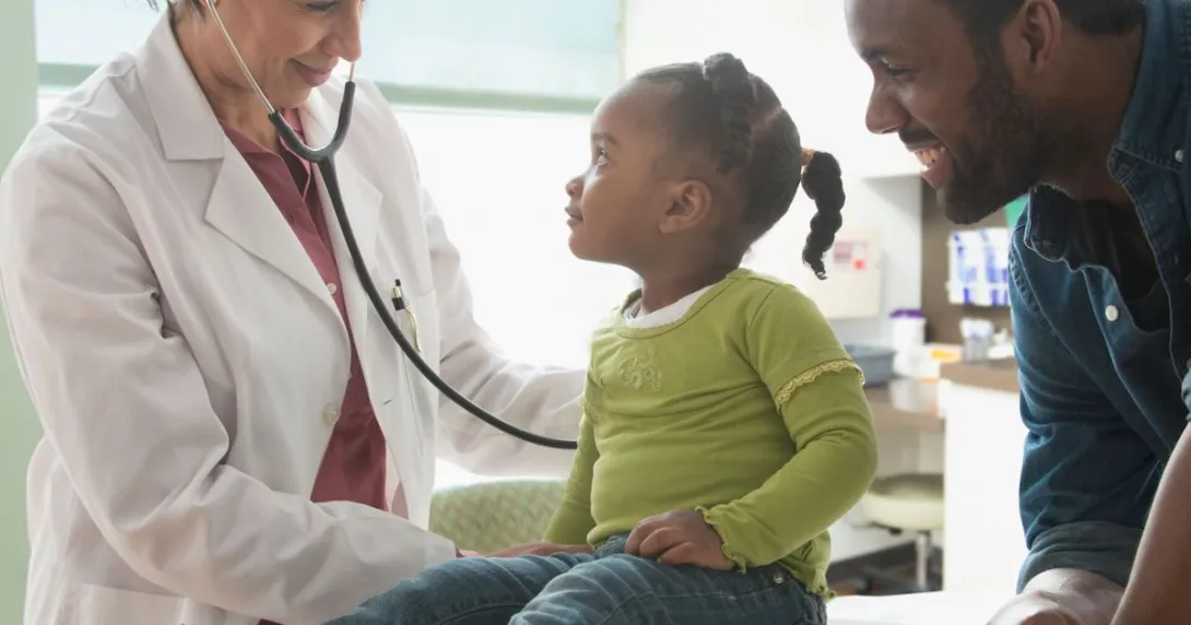 Healthcare provider examining a patient while their caregiver stands nearby watching Healthcare provider examining a patient while their caregiver stands nearby watching