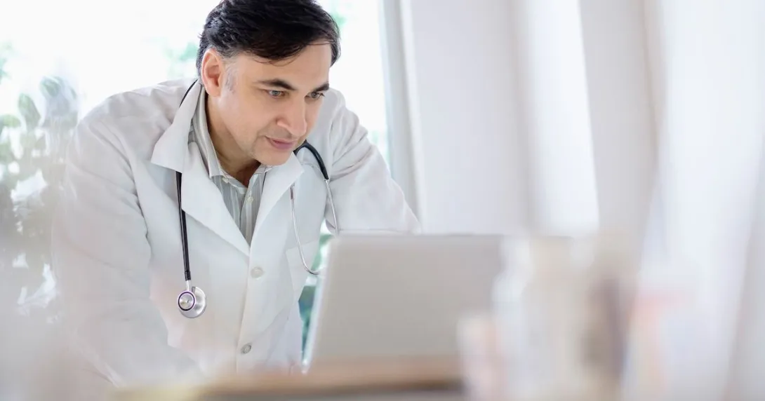 Healthcare provider wearing a lab coat with a stethoscope around their neck while looking at a computer
Healthcare provider wearing a lab coat with a stethoscope around their neck while looking at a computer