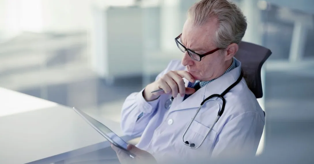 Healthcare provider looking at a tablet while holding their chin as though deep in thought
Healthcare provider looking at a tablet while holding their chin as though deep in thought