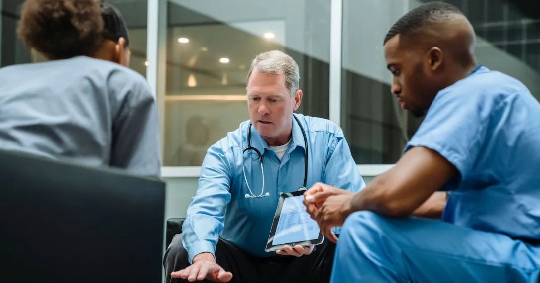 Three healthcare providers sitting around a table looking at a tablet
Three healthcare providers sitting around a table looking at a tablet