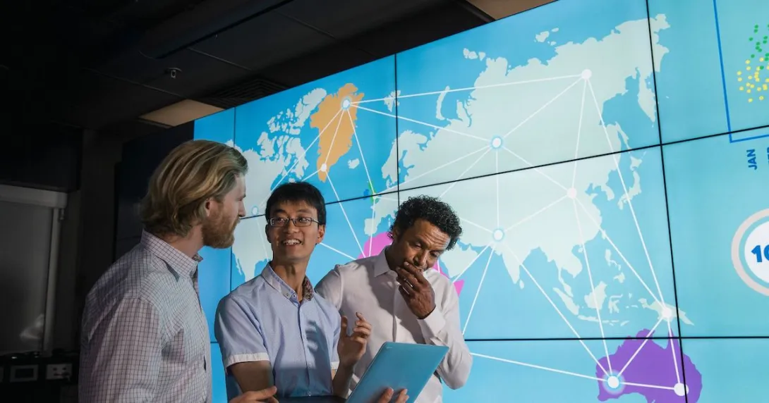 Three people standing in front of a world map Three people standing in front of a world map