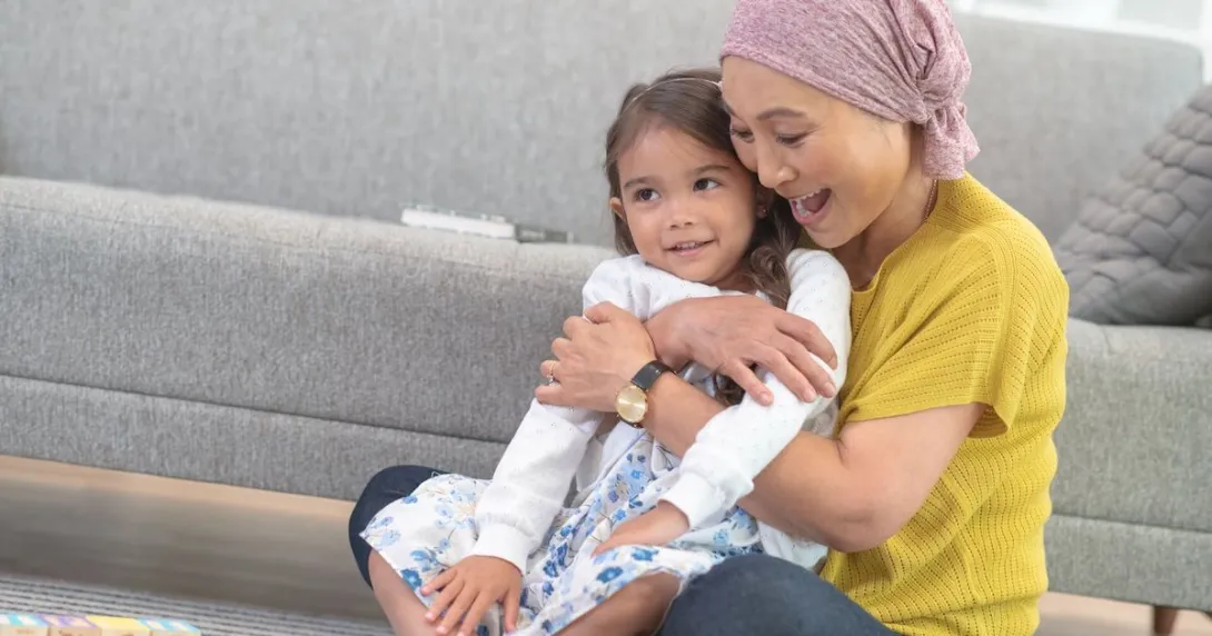 Two people sitting on the floor next to a couch with one wearing a head scarf