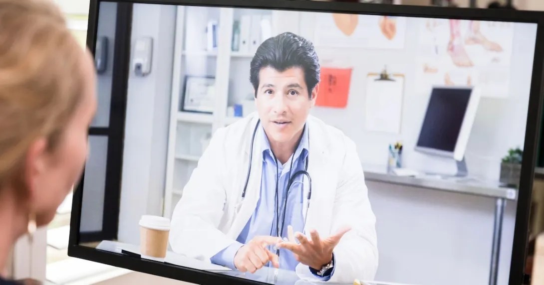 Healthcare provider on a computer screen talking to someone sitting at a desk Healthcare provider on a computer screen talking to someone sitting at a desk