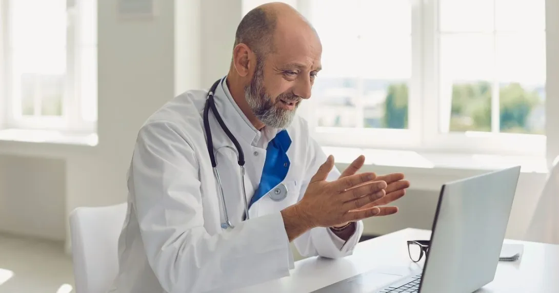 A doctor conducting a virtual consultation with a patient using a laptop