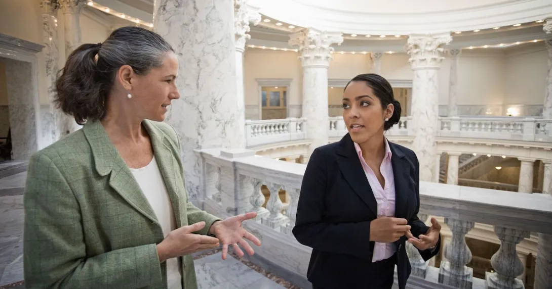 Two people walking through a federal building while talking to each other Two people walking through a federal building while talking to each other