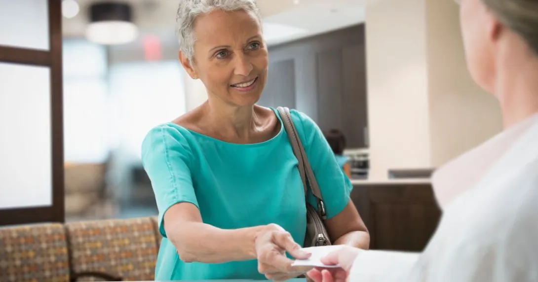 Person handing a piece of paper to a pharmacist Person handing a piece of paper to a pharmacist