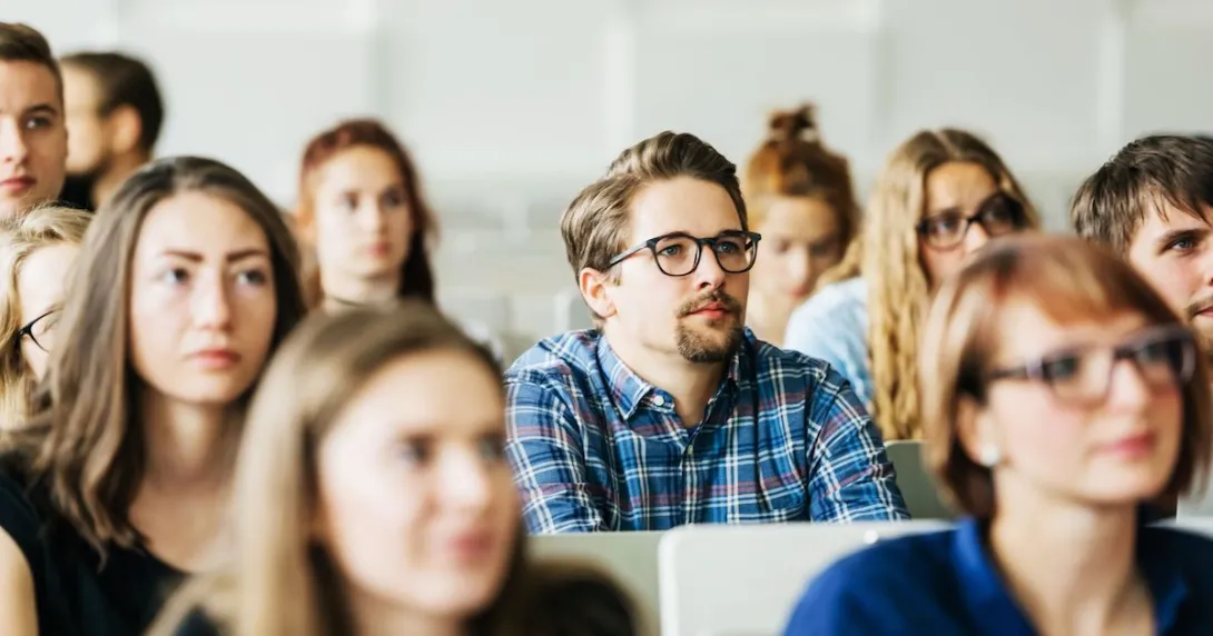 Numerous students sitting in a classroom with a vantage point from the front
Numerous students sitting in a classroom with a vantage point from the front