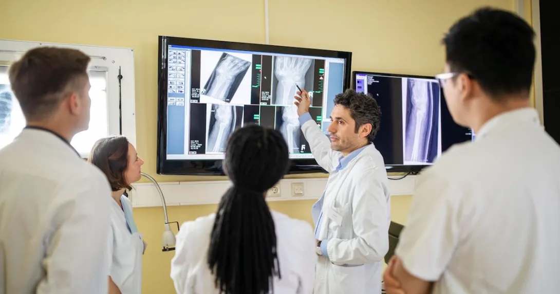 A group of clinicians discussing an X-ray report on a television screen A group of clinicians discussing an X-ray report on a television screen