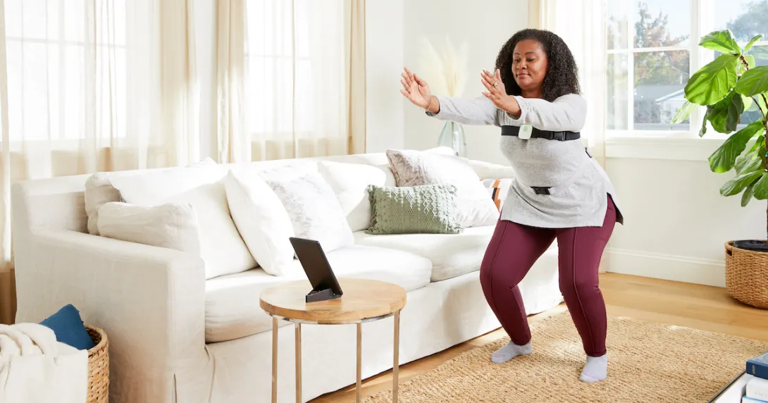 A woman wearing Hinge sensors performing exercises guided via a tablet A woman wearing Hinge sensors performing exercises guided via a tablet