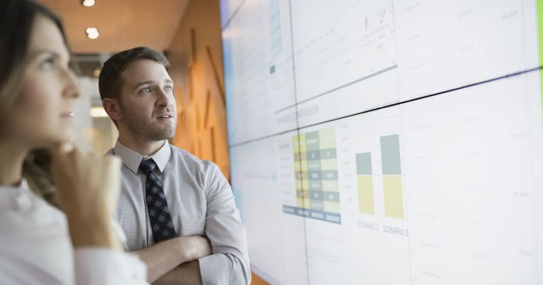 Two people looking at a screen with graphs on it Two people looking at a screen with graphs on it