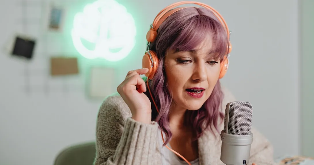 ASMRtist wearing orange headphones and whispering into a microphone at their desk