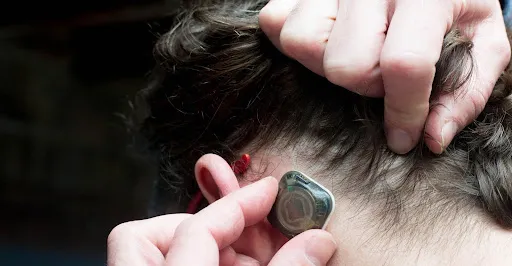 A person pulling back their hair to place the sensor A person pulling back their hair to place the sensor