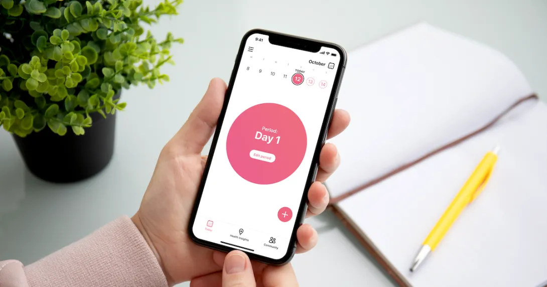 A person holding a smartphone displaying the app. The screen reads, "Period: Day 1." A person holding a smartphone displaying the app. The screen reads, "Period: Day 1."
