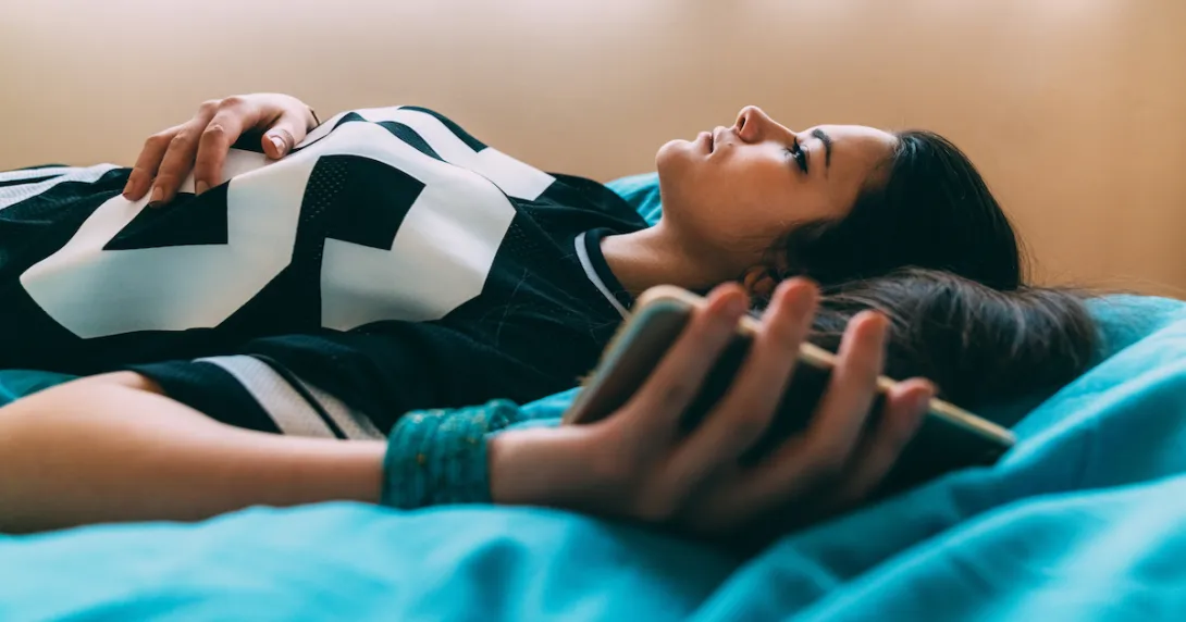 Person lying on a bed while holding a phone Person lying on a bed while holding a phone