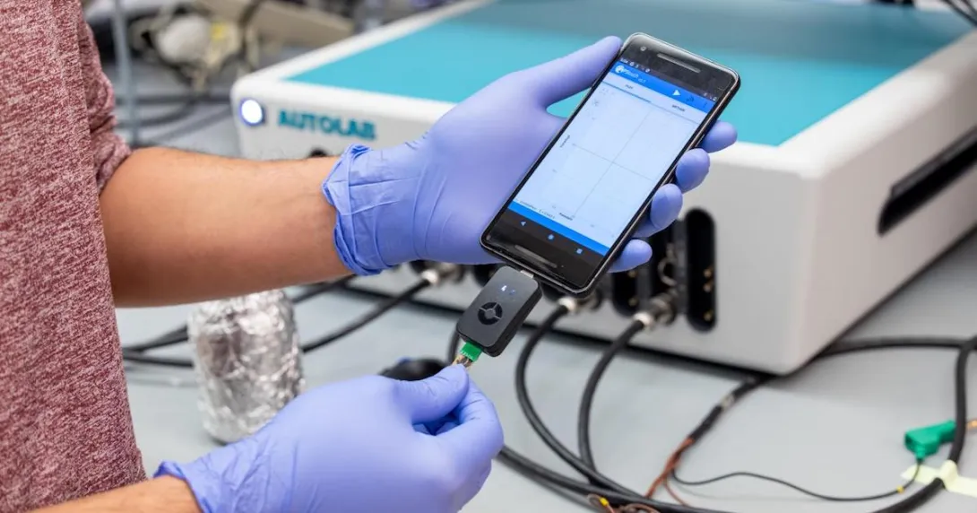 Penn researcher holding a smartphone as it uses the RAPID test to detect COVID-19