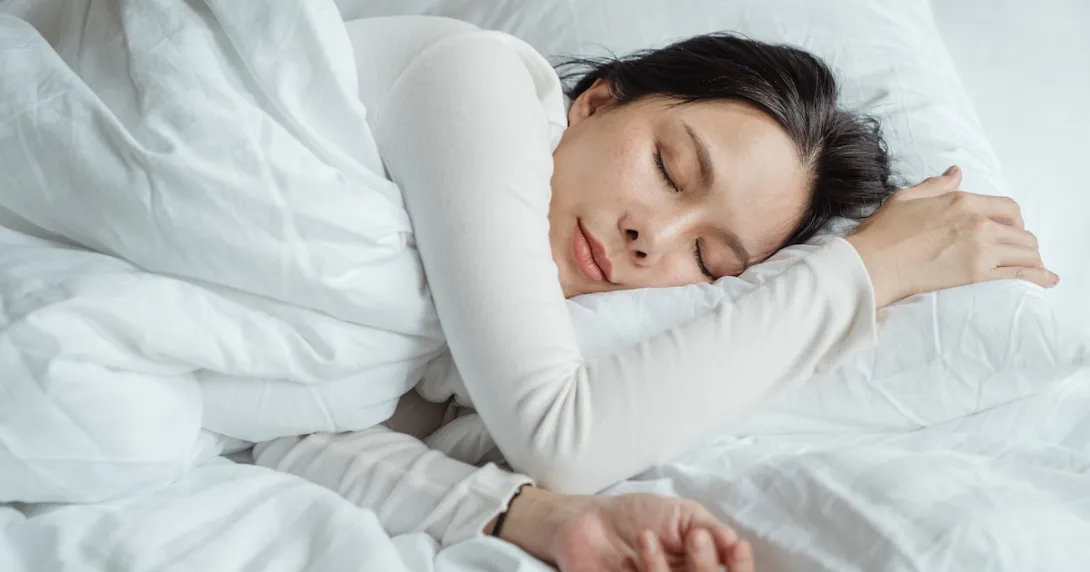 Woman sleeping in an all white bed