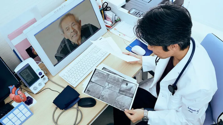 Doctor consults x-ray scans while on video call with a patient