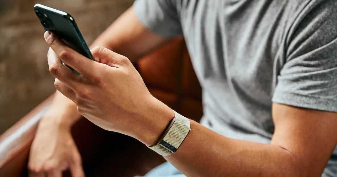 A close up of a man wearing the WHOOP 4.0 on his wrist while using a smartphone A close up of a man wearing the WHOOP 4.0 on his wrist while using a smartphone